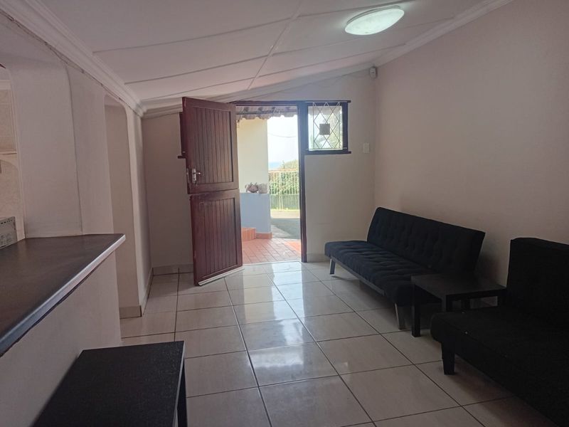 A living area featuring tiled flooring, ceiling coving, and a breakfast bar, with direct access to an outdoor patio area.