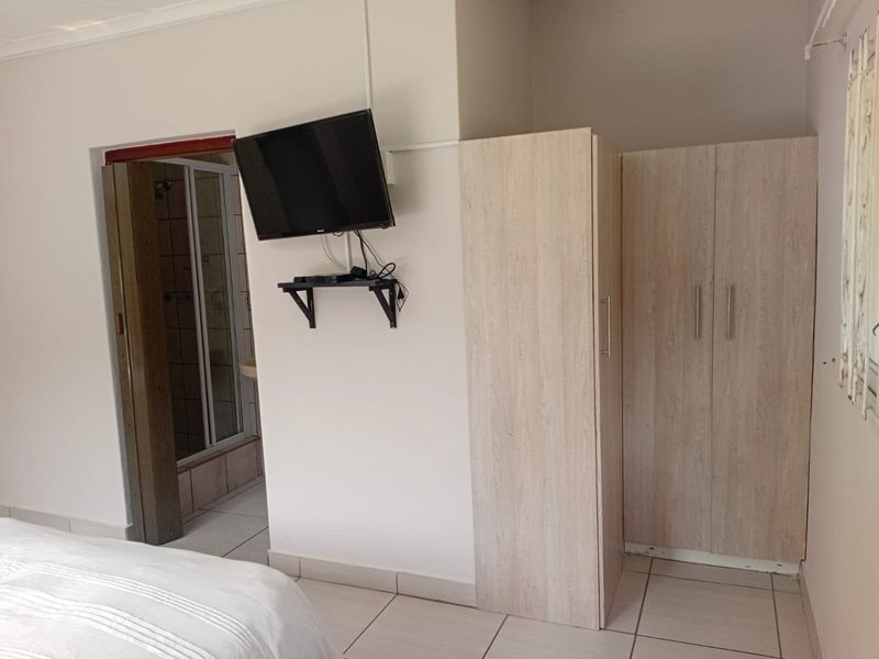 Bedroom featuring tiled flooring, built-in wardrobe storage, and direct access to an en-suite bathroom.