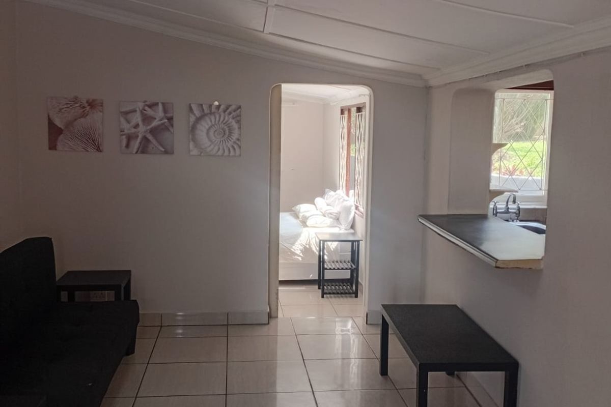 Open plan living area featuring tiled flooring, a breakfast bar pass-through to the kitchen, and direct access to the adjacent bedroom.