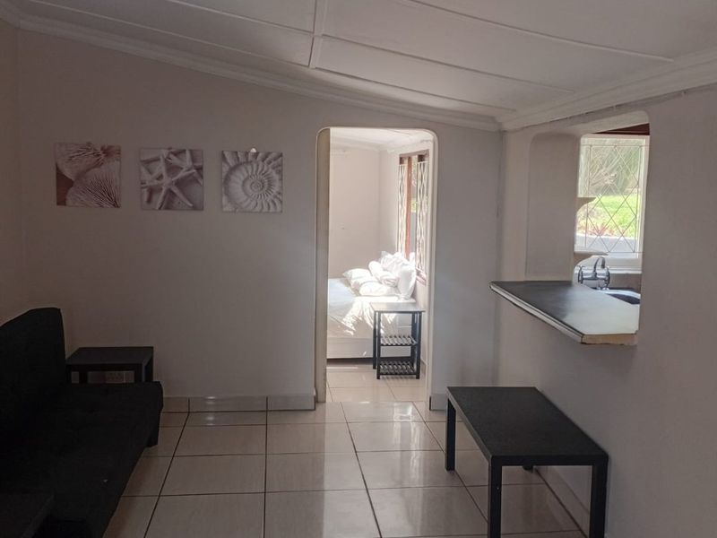 Open plan living area featuring tiled flooring, a breakfast bar pass-through to the kitchen, and direct access to the adjacent bedroom.