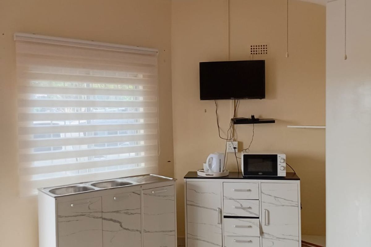 A functional kitchen area featuring tiled flooring, a stainless steel sink unit, and a ceiling fan, providing a practical space for daily use.