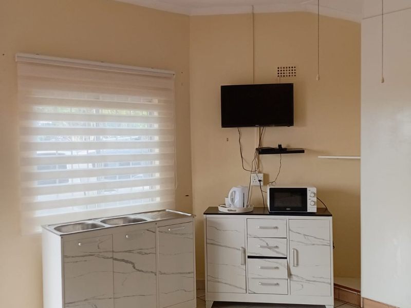 A functional kitchen area featuring tiled flooring, a stainless steel sink unit, and a ceiling fan, providing a practical space for daily use.
