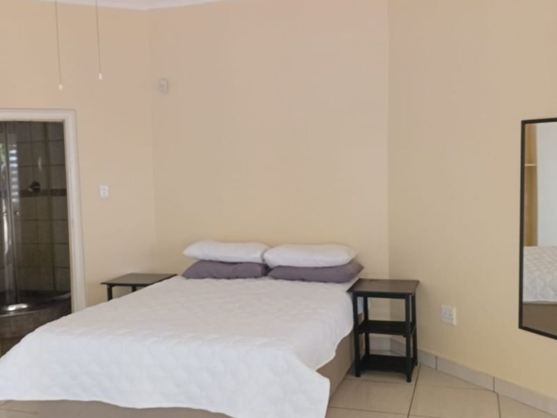 A bedroom featuring tiled flooring, a ceiling fan, and direct access to an en-suite bathroom.