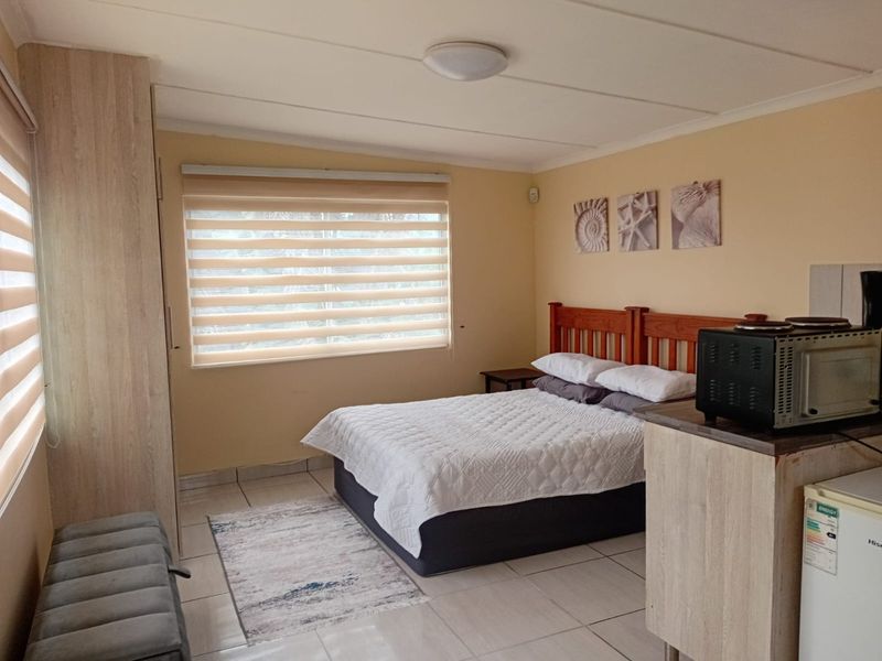 A functional bedroom featuring tiled flooring, a built-in wardrobe, and roller blinds, providing a comfortable and practical living space.