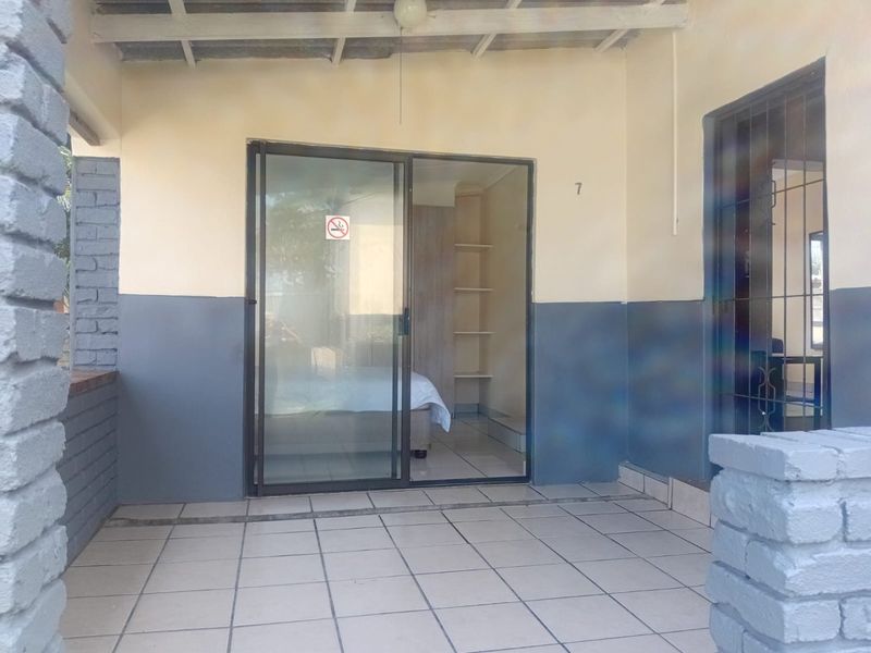 Covered patio area featuring tiled flooring, brick pillars, and a sliding glass door providing access to the interior living space.
