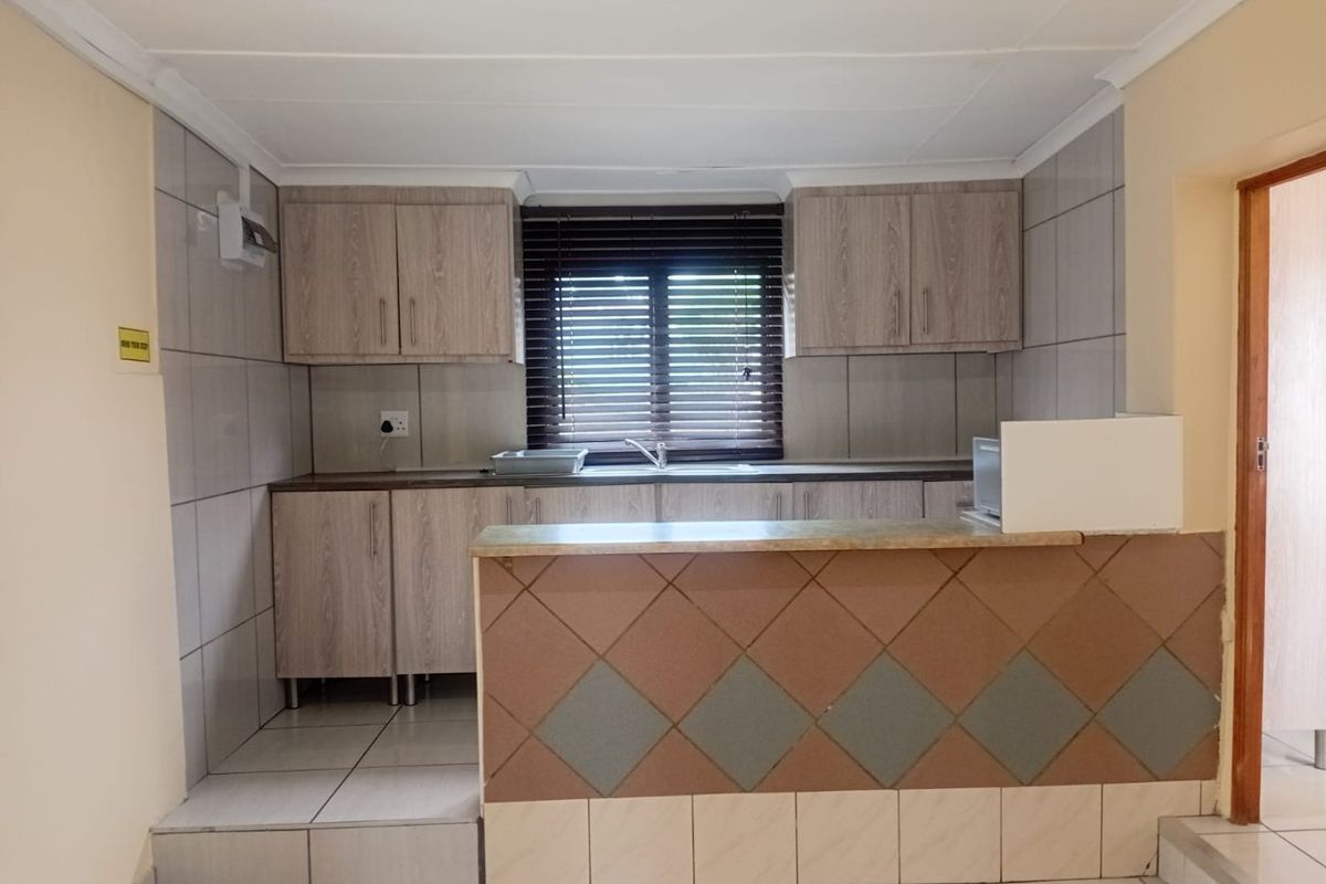A functional kitchen featuring wood-look cabinetry, tiled backsplash, and a breakfast bar counter, offering a clean and practical layout for daily use.
