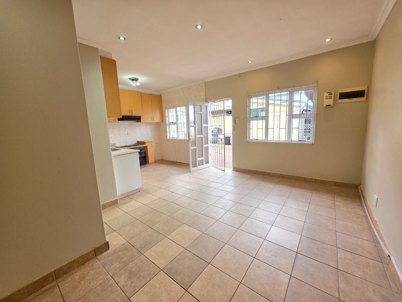An open-plan living and kitchen area featuring tiled flooring, recessed lighting, and functional built-in cabinetry, offering a blank canvas for personalization.