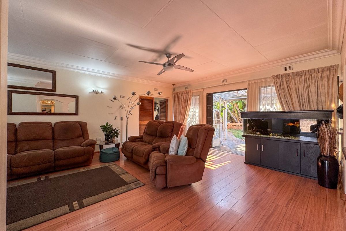 A spacious living room featuring laminate flooring, a ceiling fan, and direct access to an outdoor patio area through sliding glass doors.