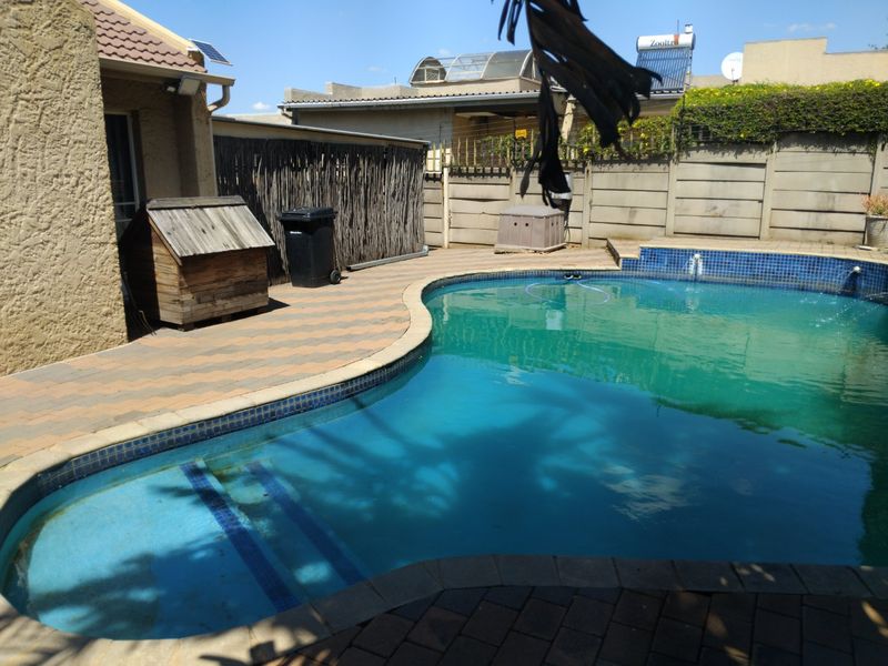 Outdoor pool area featuring a paved patio, precast concrete boundary wall, and a solar water heating system installed on the roof.