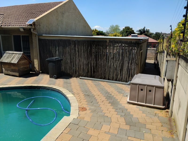 Outdoor pool area featuring a paved patio, boundary wall with electric fencing, and a swimming pool.