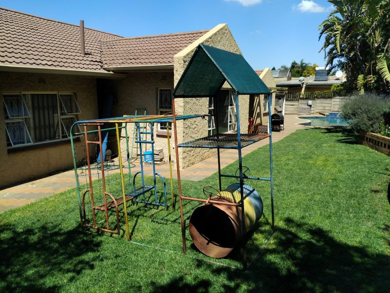 Rear view of the property featuring a paved patio area, a swimming pool, and a well-maintained lawn.