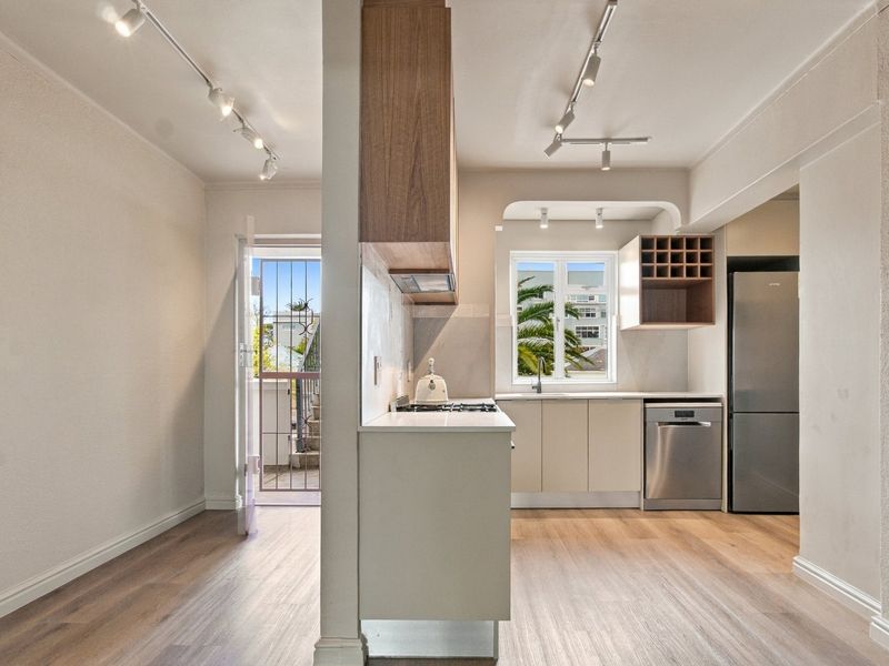 Modern kitchen featuring built-in cabinetry, gas hob, integrated dishwasher, and track lighting, with direct access to an outdoor balcony area.