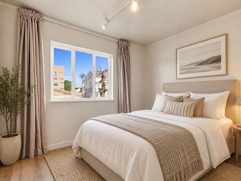 A well-maintained bedroom featuring neutral tones, track lighting, and laminate flooring, offering a bright and comfortable living space.