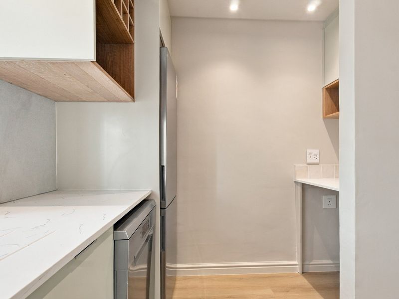 A clean and modern scullery area featuring stone countertops, built-in cabinetry, and recessed lighting, providing a functional space for utility and storage.