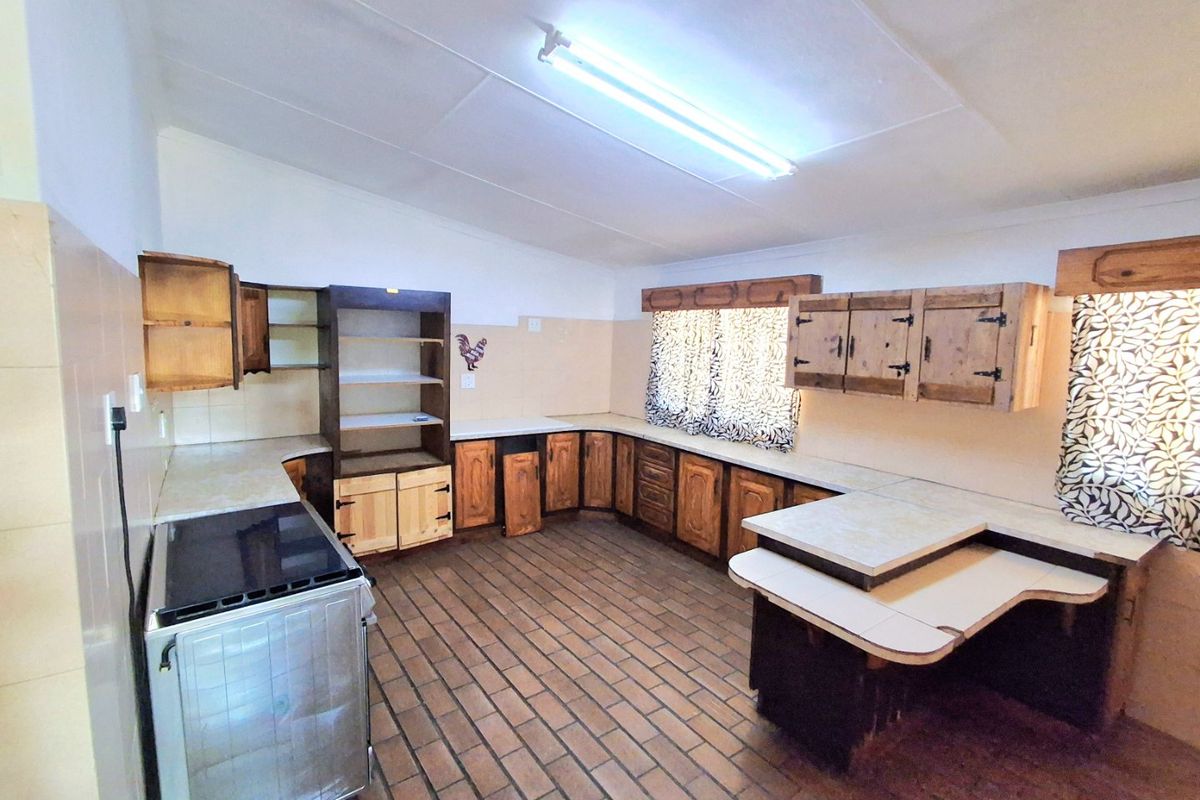 A dated kitchen featuring extensive wooden cabinetry, tiled flooring, and a tiled splashback, offering a functional layout with potential for modernization.