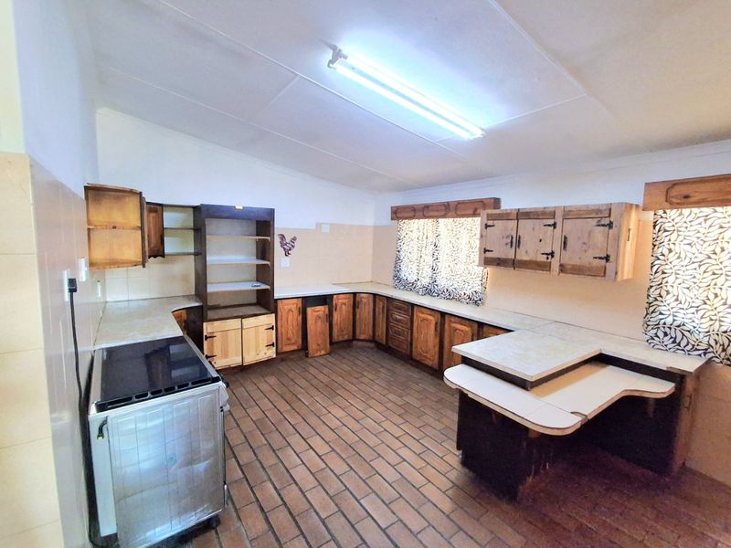 A dated kitchen featuring extensive wooden cabinetry, tiled flooring, and a tiled splashback, offering a functional layout with potential for modernization.