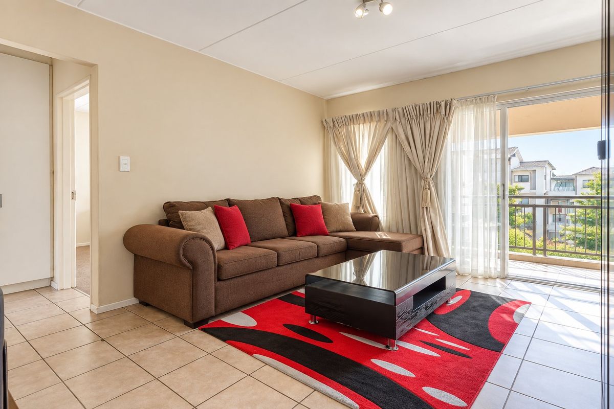 A bright living room featuring tiled flooring and a large sliding glass door providing access to an outdoor balcony area.