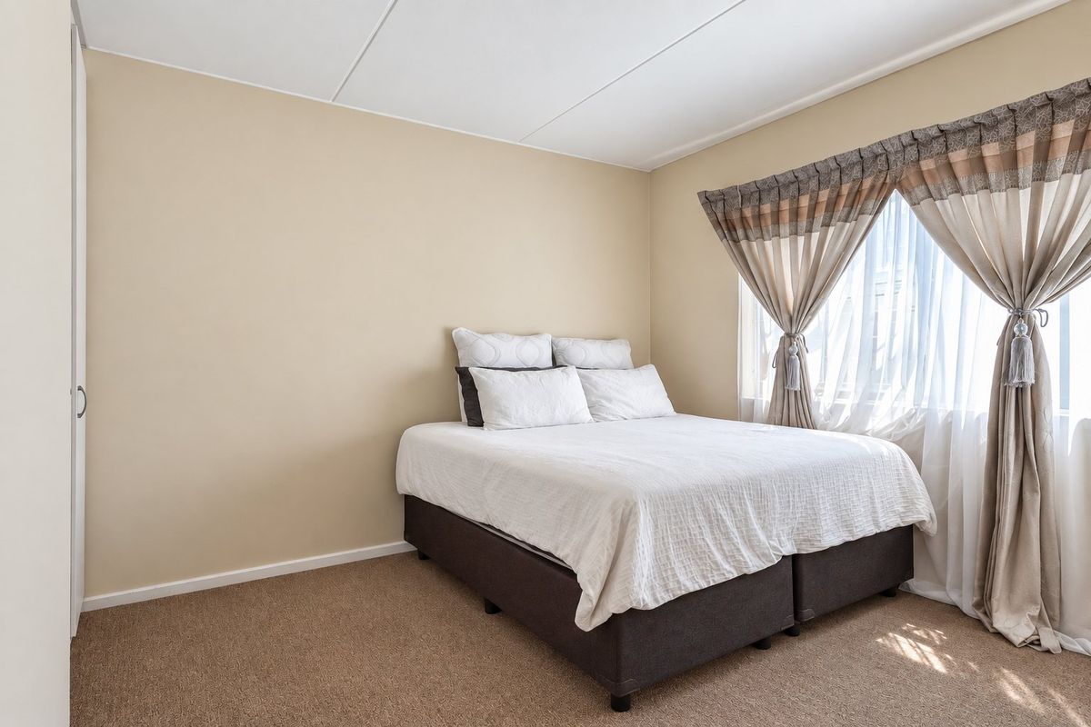 A functional bedroom featuring neutral wall tones, carpeted flooring, and a built-in wardrobe, offering a clean and simple living space.