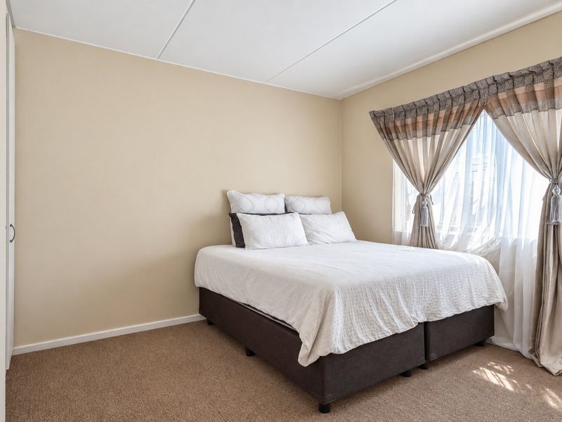 A functional bedroom featuring neutral wall tones, carpeted flooring, and a built-in wardrobe, offering a clean and simple living space.