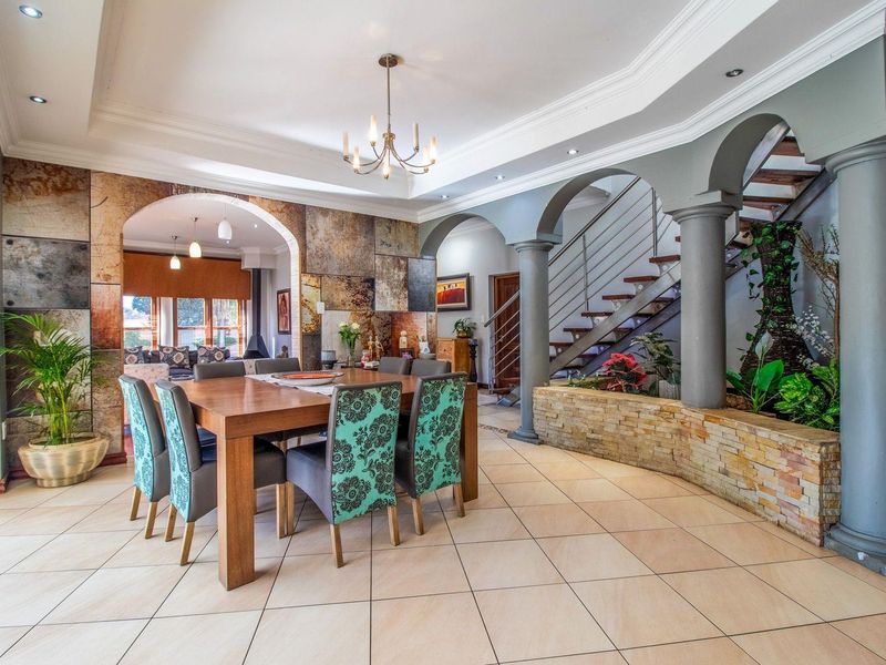 Spacious open-plan dining area featuring elegant archways, stone-clad feature walls, a grand staircase, and decorative columns with an integrated indoor planter.