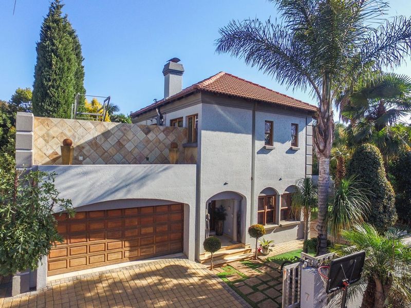 Front elevation of a two-story house featuring a tiled roof, chimney, arched entrance, and a paved driveway leading to a double garage.