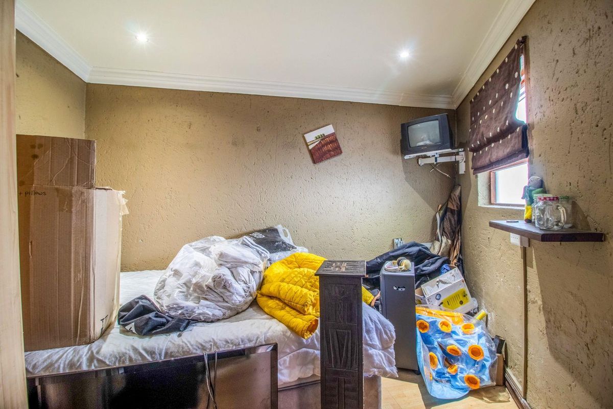 A bedroom featuring recessed downlighting, coved ceiling cornicing, and a wall-mounted television bracket, requiring cosmetic updates to improve the overall finish.