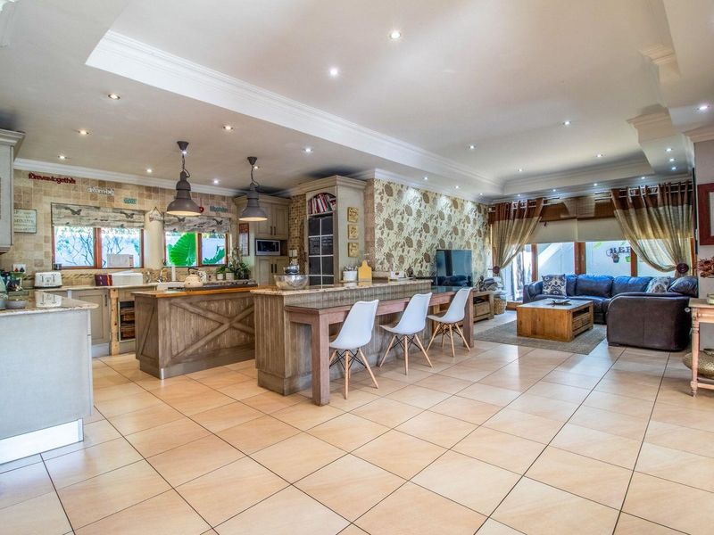 Spacious open-plan living area featuring a large kitchen with a breakfast bar, tiled flooring, and recessed lighting, seamlessly flowing into the lounge space.