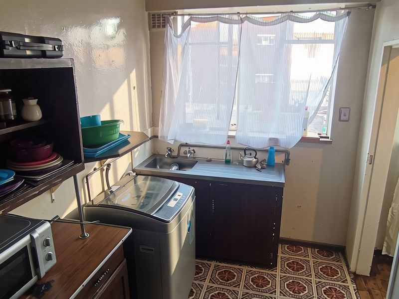 Functional laundry area featuring a stainless steel sink, patterned floor tiles, and a wall-mounted electrical distribution board.