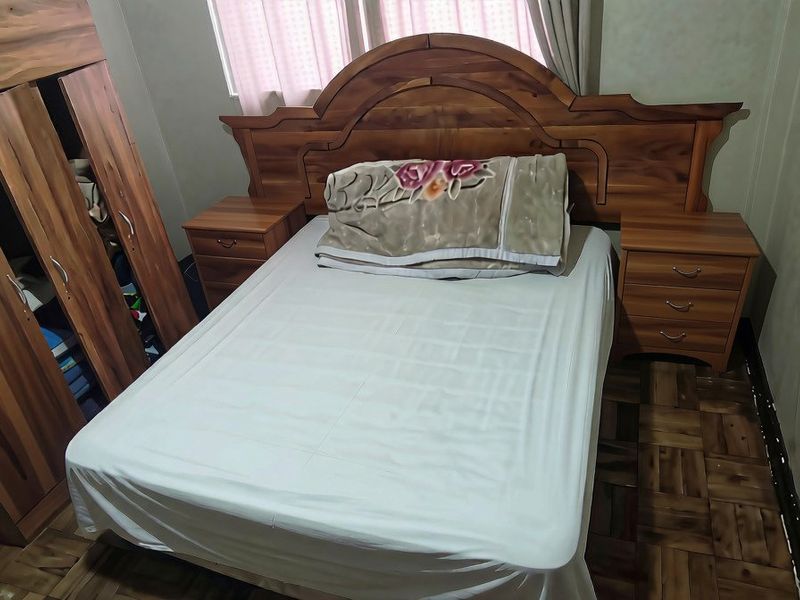 A bedroom featuring parquet flooring and neutral wall finishes, providing a functional space for rest.
