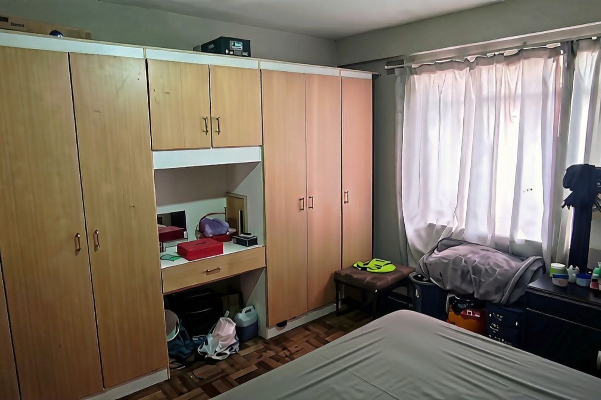 Bedroom featuring extensive built-in wooden cupboards with an integrated vanity unit and parquet flooring.