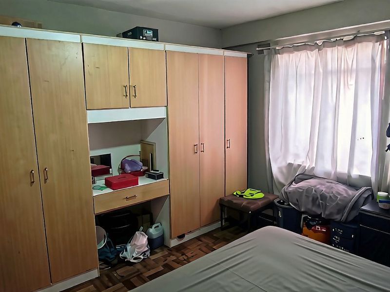 Bedroom featuring extensive built-in wooden cupboards with an integrated vanity unit and parquet flooring.