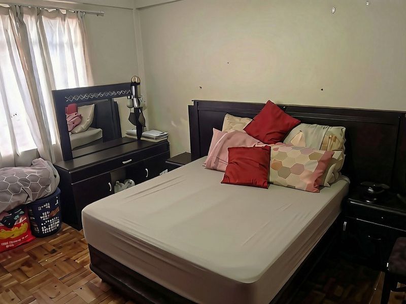 A bedroom featuring parquet flooring and large windows with curtain rails, offering a functional space ready for cosmetic updates.