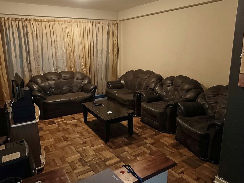 A living room featuring classic parquet flooring and neutral wall finishes, providing a functional and traditional living space.