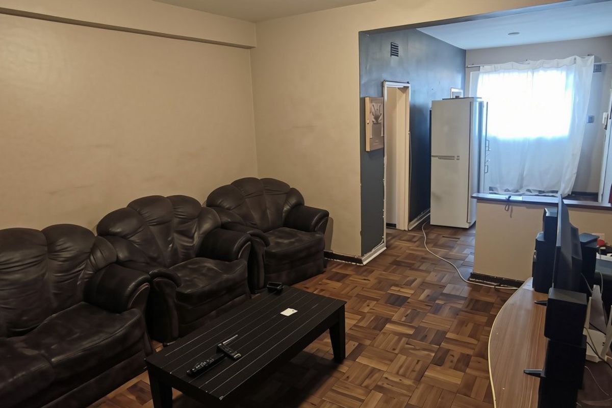 Open plan living area featuring traditional parquet flooring and a breakfast bar, offering a functional layout with potential for cosmetic updates.