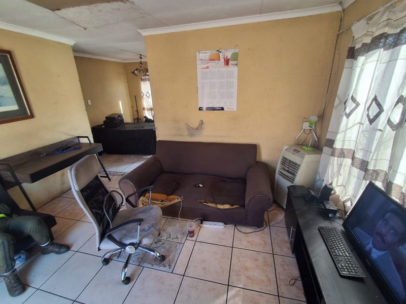 A living room space featuring ceramic floor tiles and ceiling cornicing, currently requiring significant maintenance and cosmetic updates to improve the overall condition.