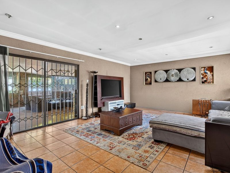 Spacious living room featuring ceramic tiled flooring, recessed downlighting, and large sliding glass doors providing access to the outdoor patio area.