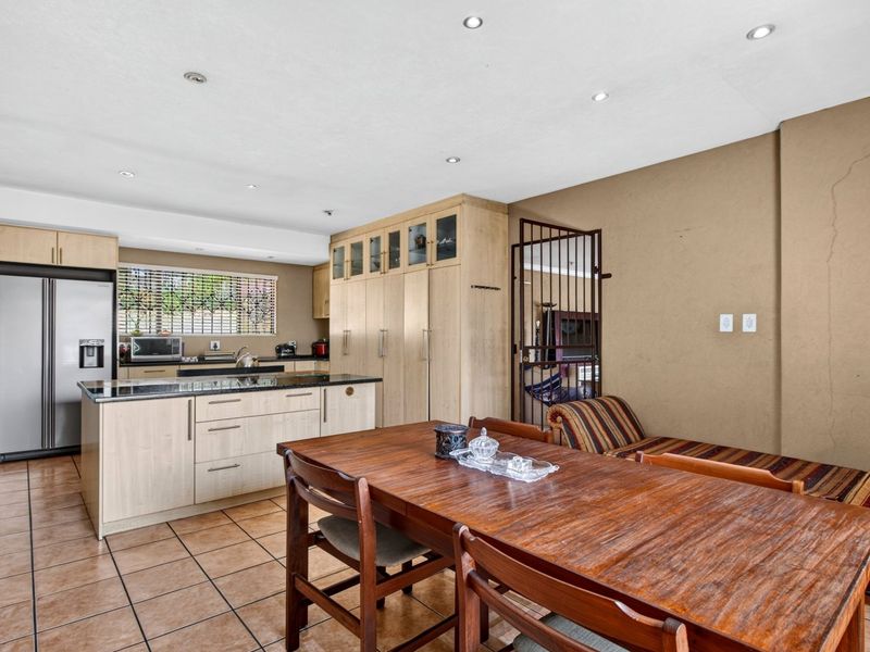 Open-plan kitchen and dining area featuring light wood cabinetry, granite countertops, tiled flooring, and recessed lighting.