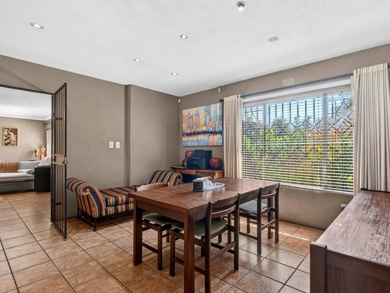 Dining room featuring tiled flooring, recessed downlighting, and a security gate leading to an adjacent living area.