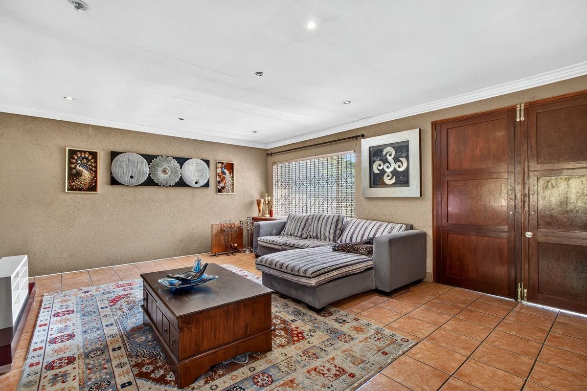 A living room featuring ceramic floor tiles, recessed downlights, and a solid wooden double door with an integrated security gate.