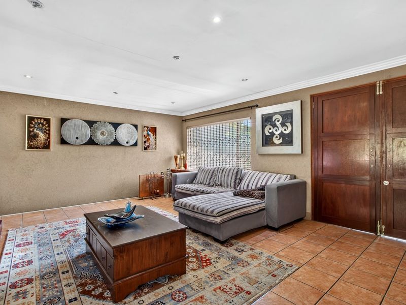 A living room featuring ceramic floor tiles, recessed downlights, and a solid wooden double door with an integrated security gate.