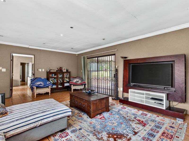 Spacious living room featuring tiled flooring, a built-in media unit, and sliding glass doors providing access to the outdoor area.