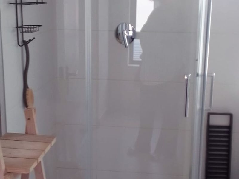 A clean bathroom featuring a glass-enclosed shower with a modern rain shower head and tiled flooring.