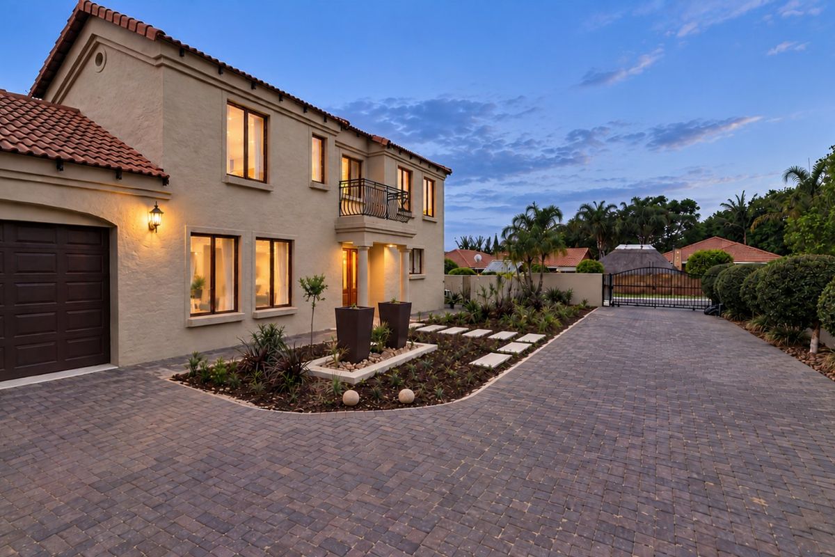 A well-maintained front exterior featuring a paved driveway, terracotta roof tiles, and a landscaped garden bed leading to the main entrance.