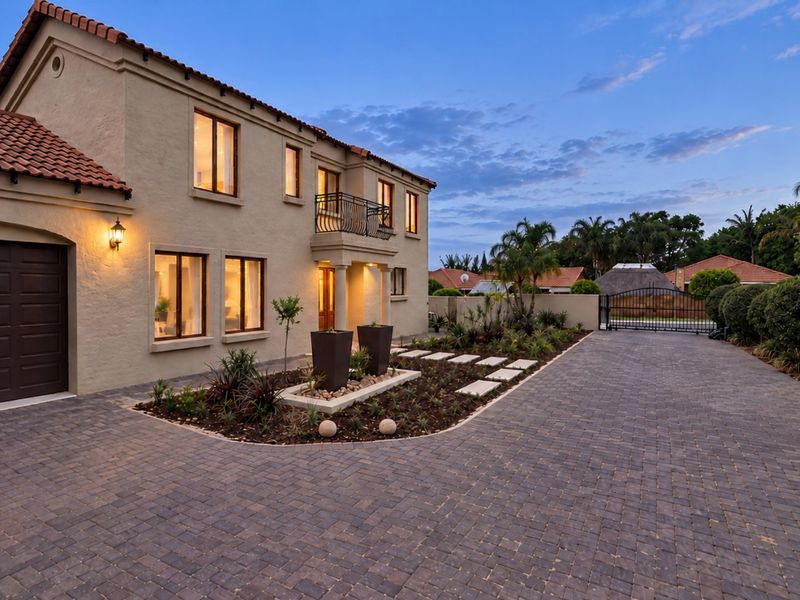 A well-maintained front exterior featuring a paved driveway, terracotta roof tiles, and a landscaped garden bed leading to the main entrance.