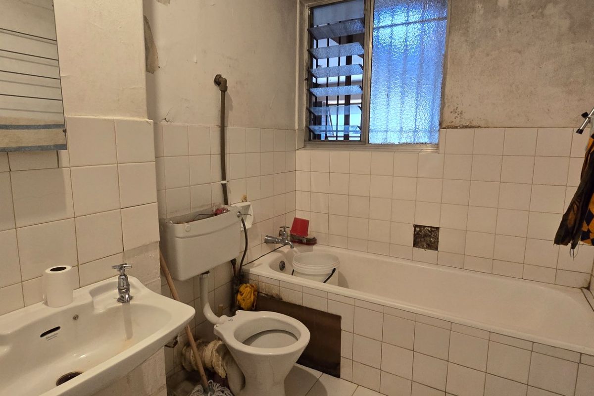 A dated bathroom featuring a bathtub, pedestal basin, and toilet, requiring significant renovation and cosmetic updates to improve its condition and functionality.