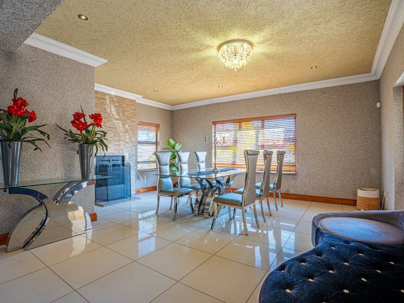 Spacious dining room featuring polished tiled flooring, a built-in fireplace, and textured wall finishes with recessed lighting.