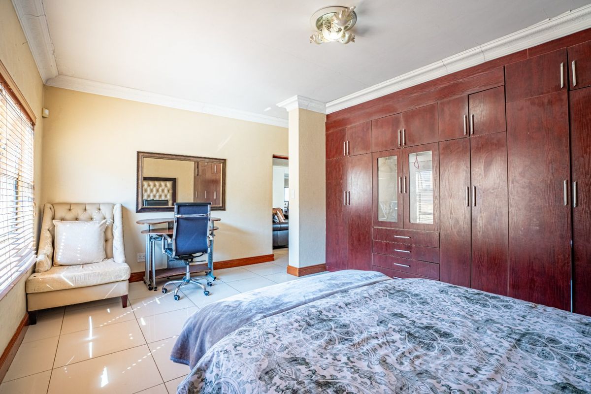 A bedroom featuring extensive built-in wooden cabinetry, tiled flooring, and decorative ceiling cornicing, offering ample storage space.