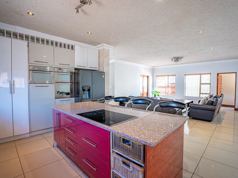 Spacious open-plan kitchen and living area featuring a central island with a built-in hob, granite countertops, and modern cabinetry.