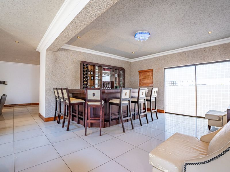 A dedicated bar area featuring a built-in wooden bar counter with integrated wine storage, tiled flooring, and sliding glass doors leading outdoors.