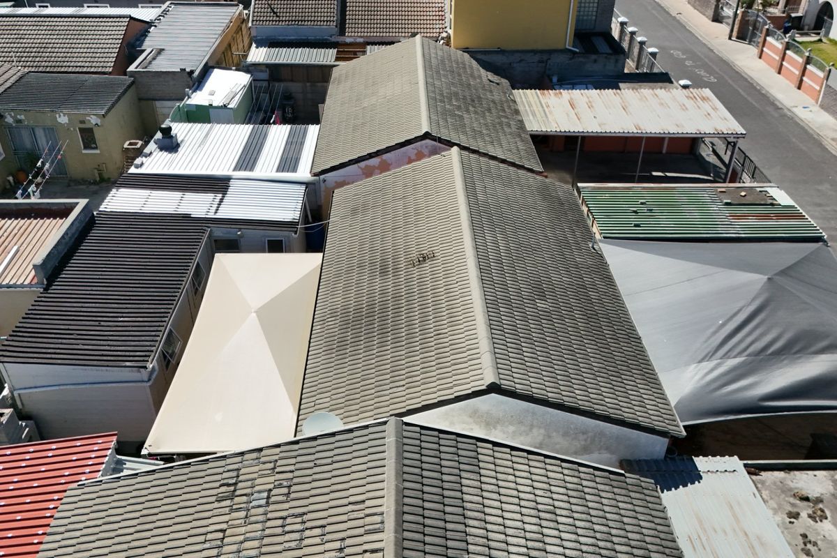 Aerial view of the property showing multiple roof sections, including tiled and corrugated metal roofing, with visible signs of weathering and maintenance requirements.
